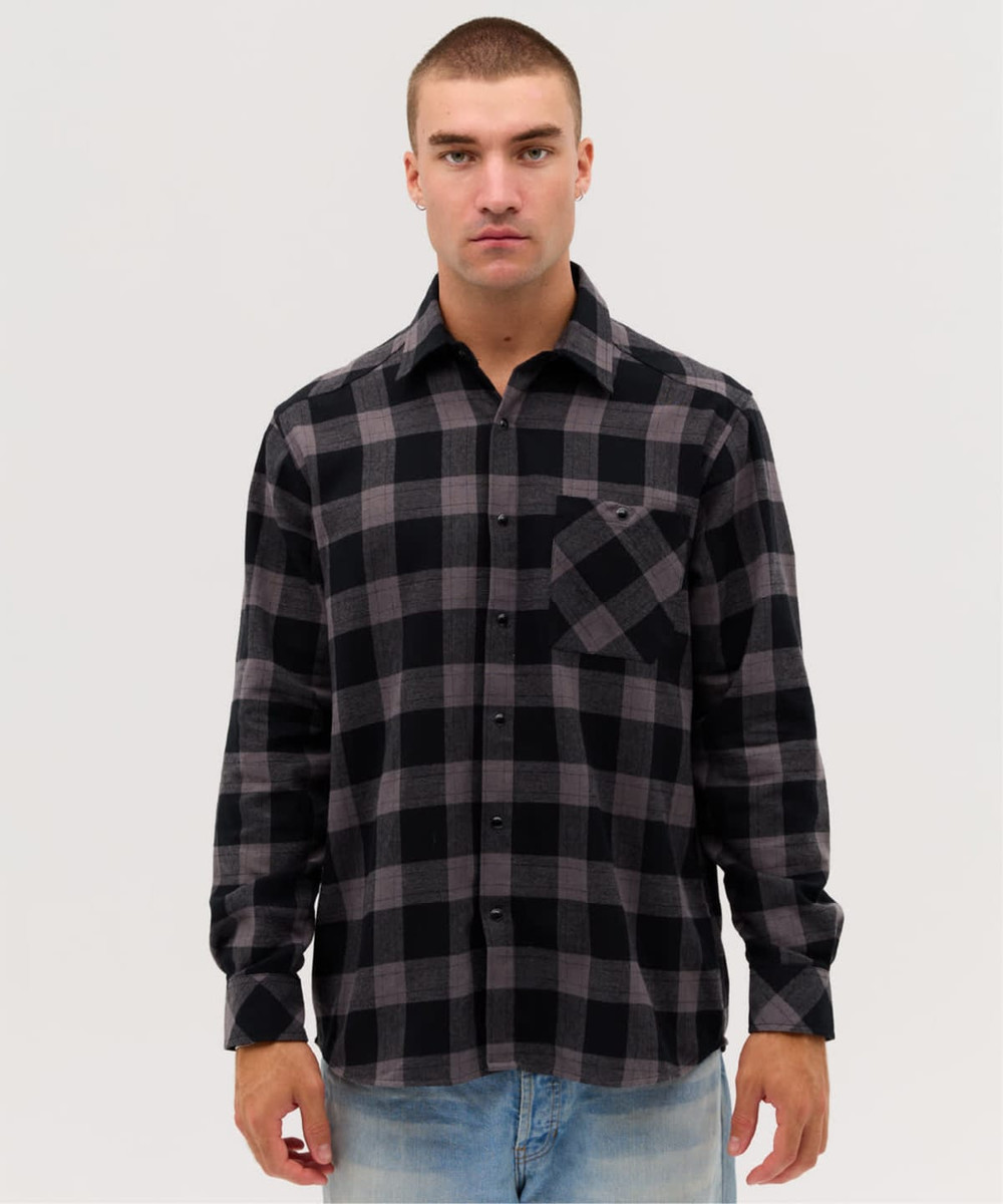 A long sleeve button-up shirt in black and grey check pattern with a single chest pocket. Features a logo.