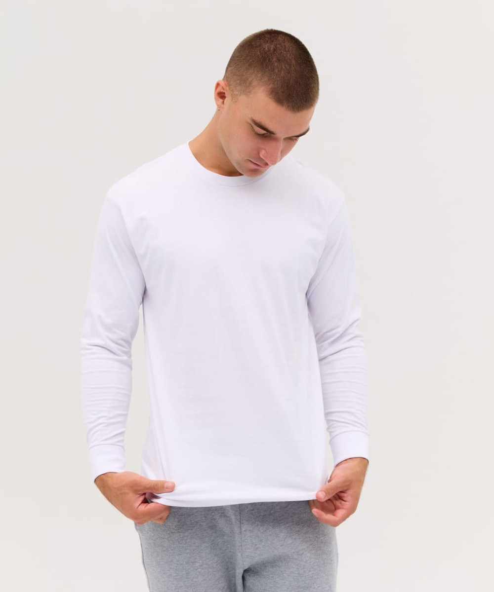 A long sleeve white tee displayed on a model, featuring a simple design and a logo on the garment.