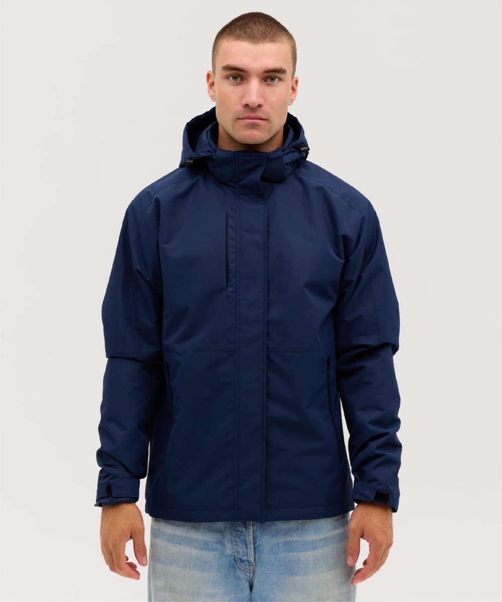 A navy blue soft shell jacket with a hood, features a front zip and a logo. Styled on a model against a neutral background.
