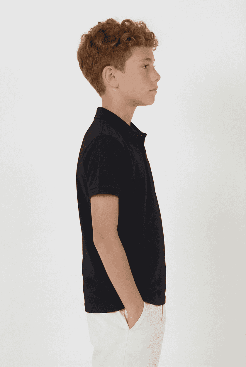 A side view of a youth in a black polo shirt, featuring short sleeves and a collar. The shirt has a logo.