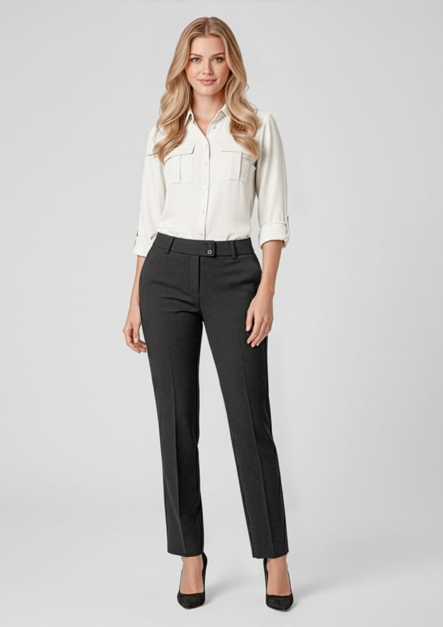 A woman wearing black slacks with a white blouse and high heels, standing against a light background. The outfit has a polished look.