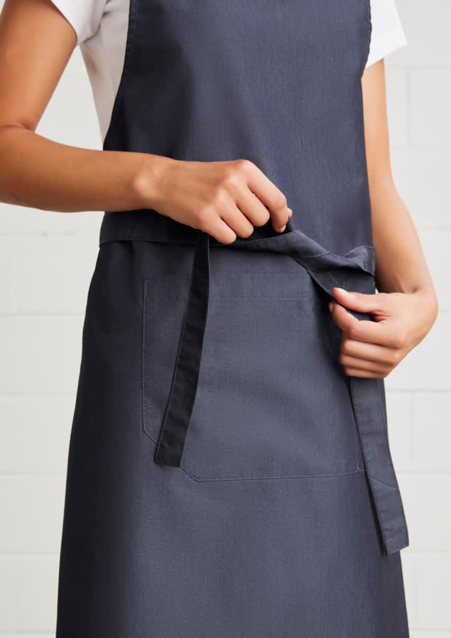 A navy blue Urban Bib Apron featuring a front pocket and adjustable tie at the waist, with branding visible.