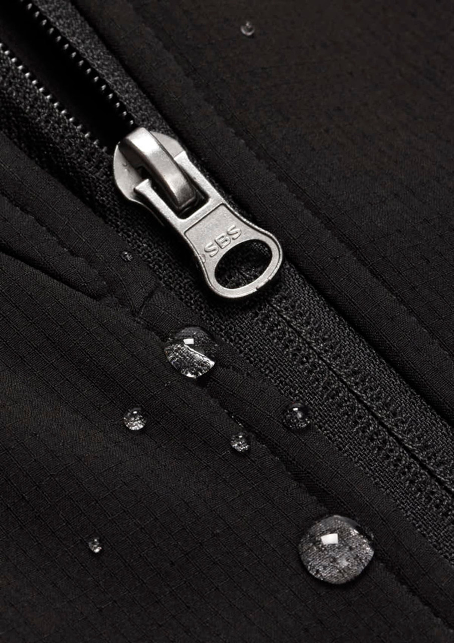 A close-up of a black soft shell jacket featuring a zipper and droplets of water on the fabric.