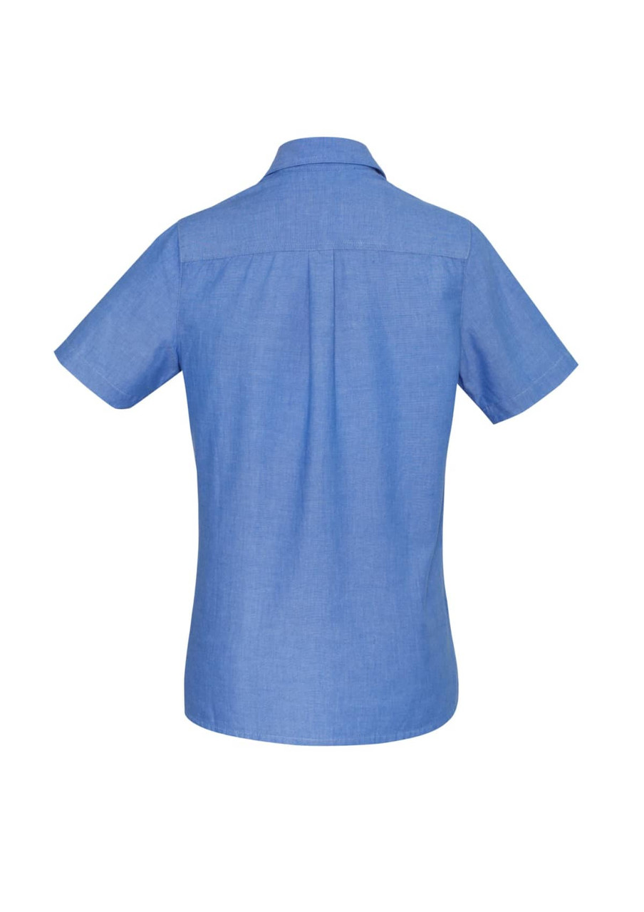 A short-sleeve women's chambray button-up shirt in light blue with a simple design and a logo on the back.
