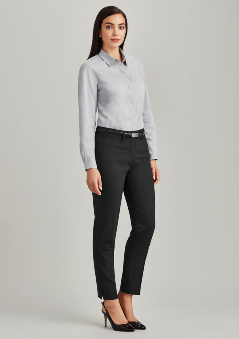 A model wears women's slim leg pants in black, paired with a light grey shirt and black heels. Features branding on the pants.