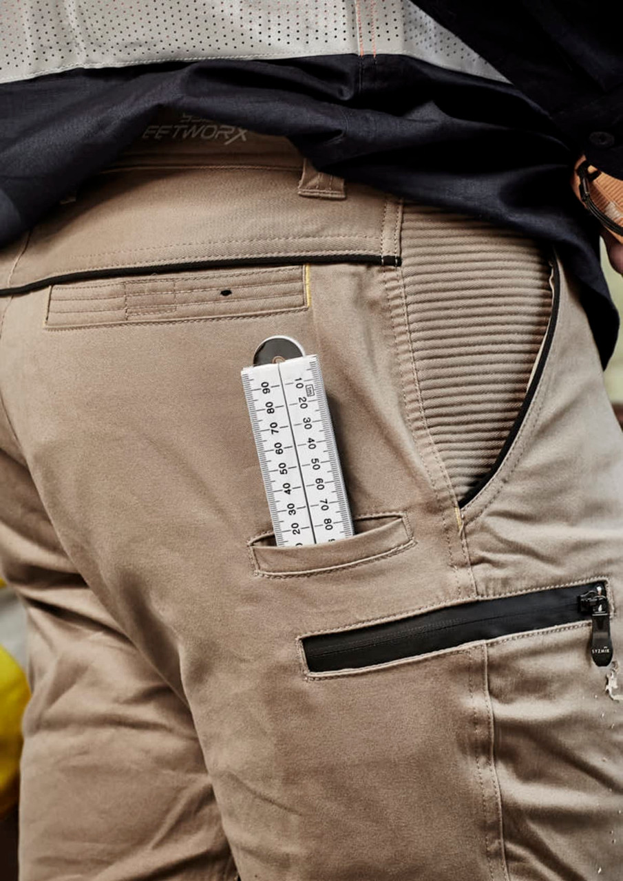 Men's street-style stretch pants in grey with cuffed hems, featuring side pockets and a ruler in the back pocket.