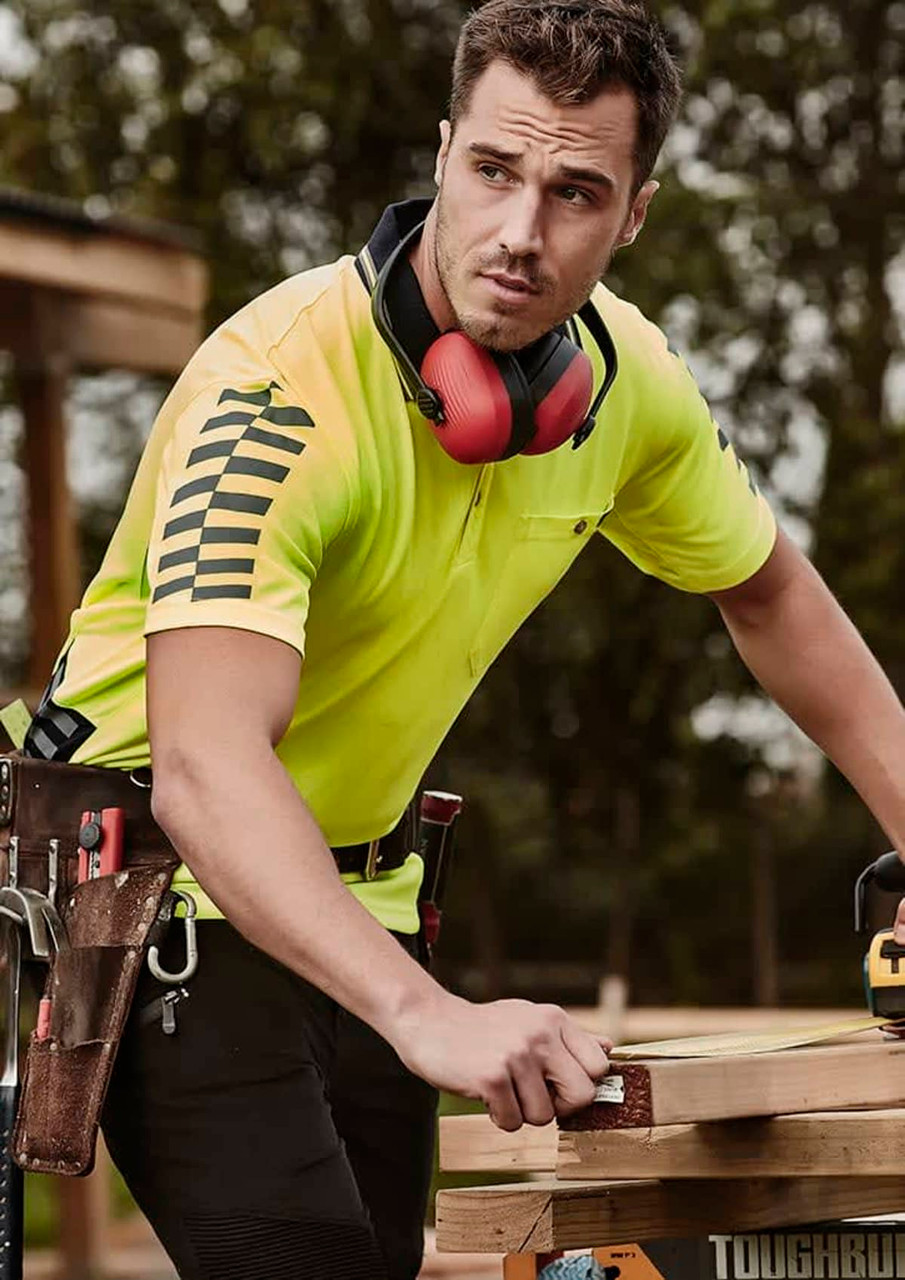 Men's short sleeve polo shirt in bright yellow with reflective stripes, featuring a logo and worn by a man at a worksite.