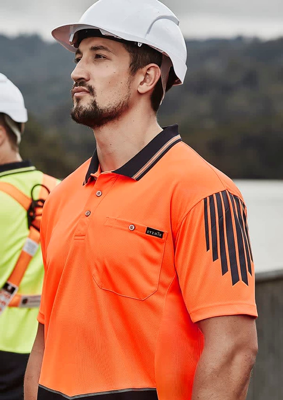 An orange short sleeve polo shirt featuring a logo and black striped design, worn by a man in a hard hat.