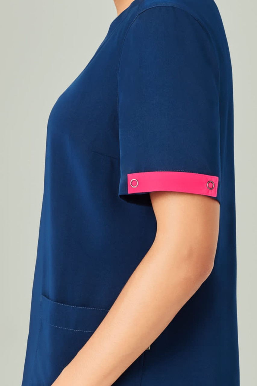 Unisex navy scrub top with pink accents on the sleeves, featuring a side pocket and a circular logo detail.