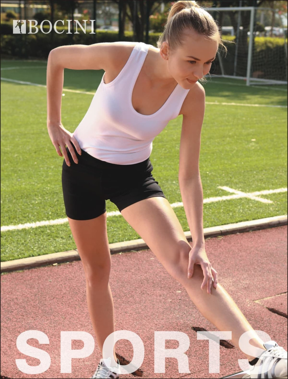 Black ladies gym shorts paired with a white tank top, on a sports field with a person stretching.