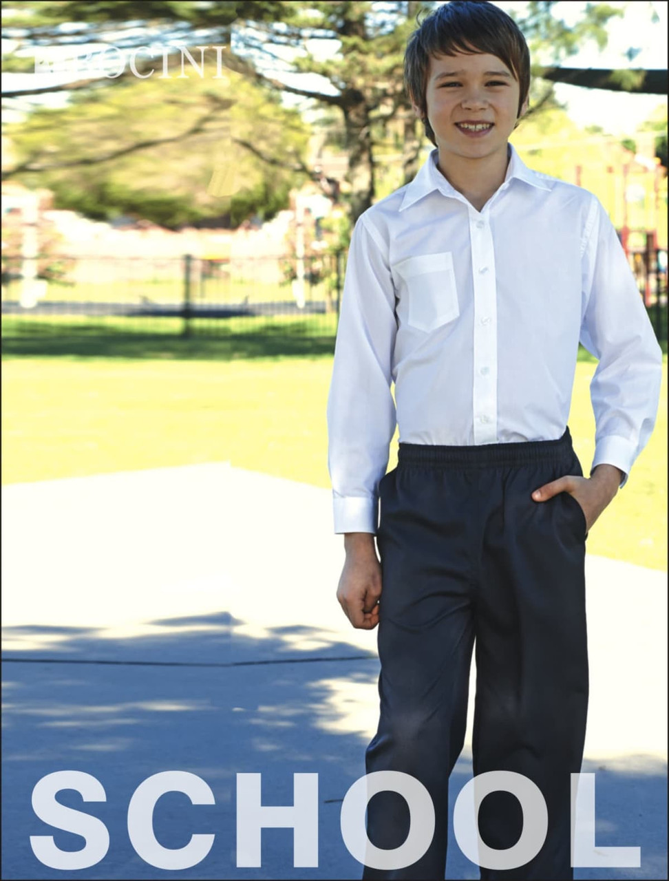A young boy in a white shirt and dark grey trousers stands outdoors. The trousers have an elastic waistband and a logo.