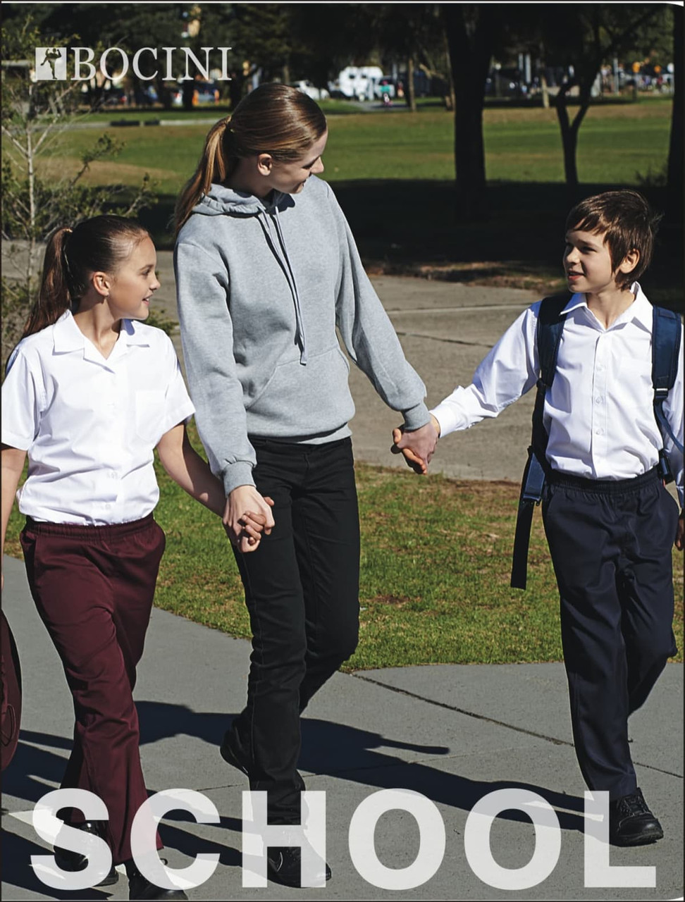 A long sleeve white button-up school shirt worn by a child, paired with dark trousers, amidst a school setting.