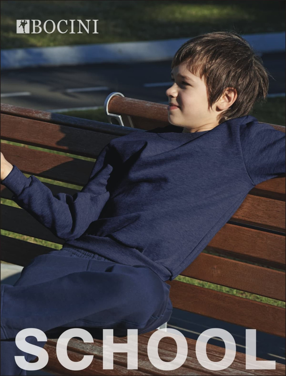 A navy blue kids' crew neck fleece jumper displayed on a bench, featuring a logo.