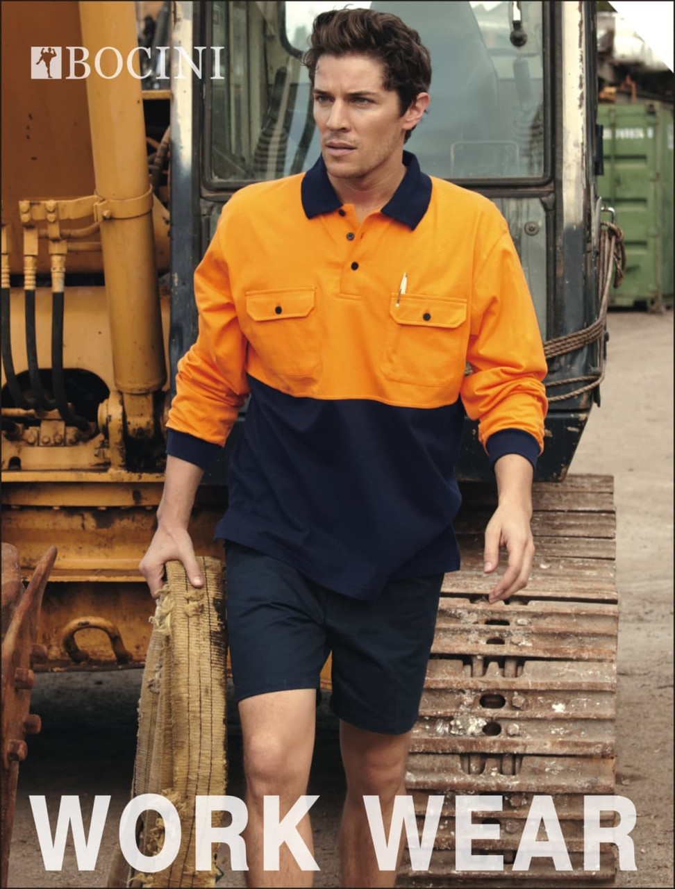 A man is wearing a hi-vis orange and navy long-sleeve polo shirt, standing near a construction vehicle.