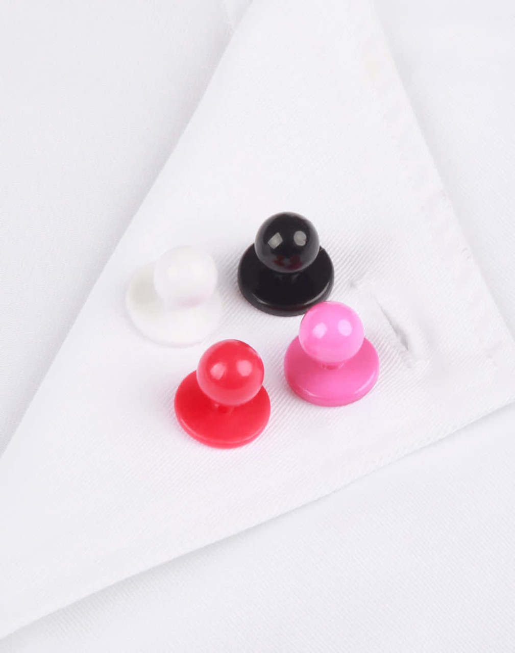 A set of four exchangeable buttons in white, black, red, and pink resting on a white chef uniform.