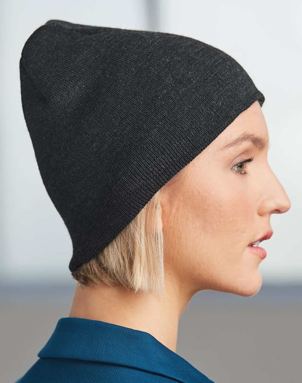 Acrylic knitted marl beanie in dark grey, displayed on a model's head from the side, featuring a simple design.
