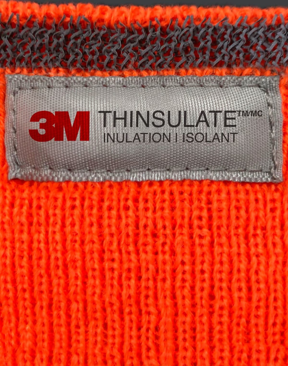 An orange Thinsulated cuff beanie with a grey label featuring branding and care information.