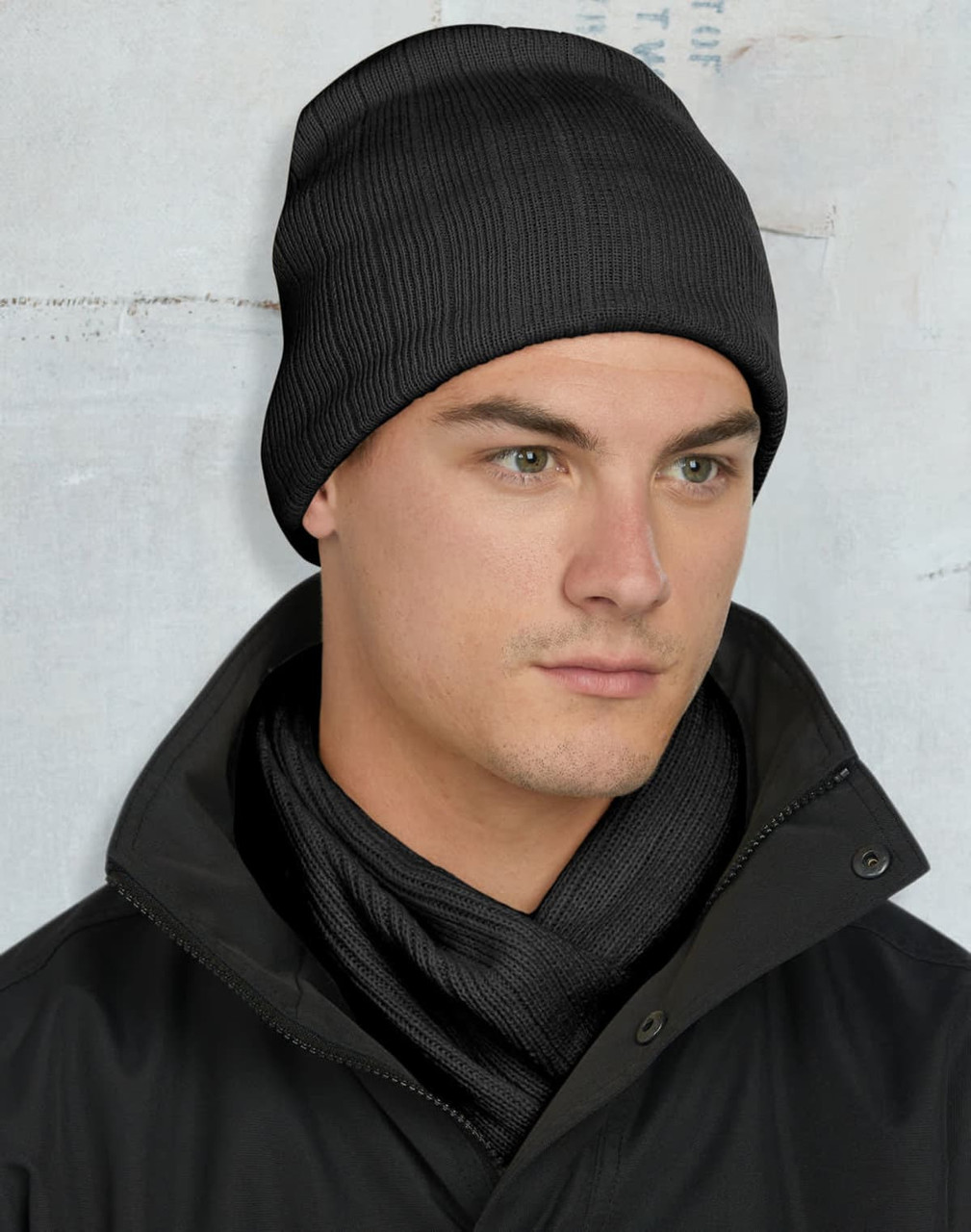 A cable knit beanie in dark green with a fleece headband inside and a logo.
