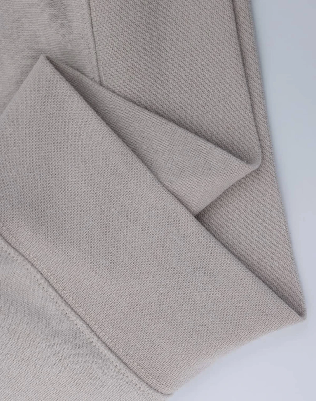 A close-up of a light beige polar fleece jumper featuring a half-zip collar. It has a simple design with a logo.