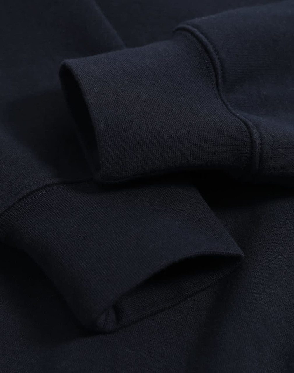 A close-up of a navy polar fleece jumper featuring half zip collar and ribbed cuffs with an unobtrusive logo.