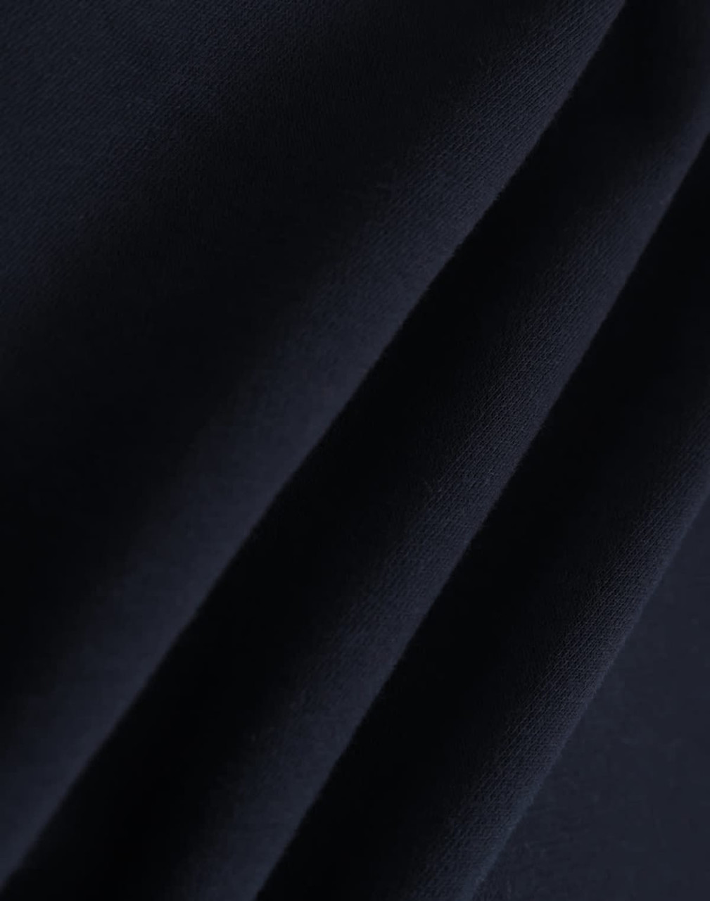A close-up of dark navy polar fleece fabric showing soft, smooth texture folds. It features a branding logo.
