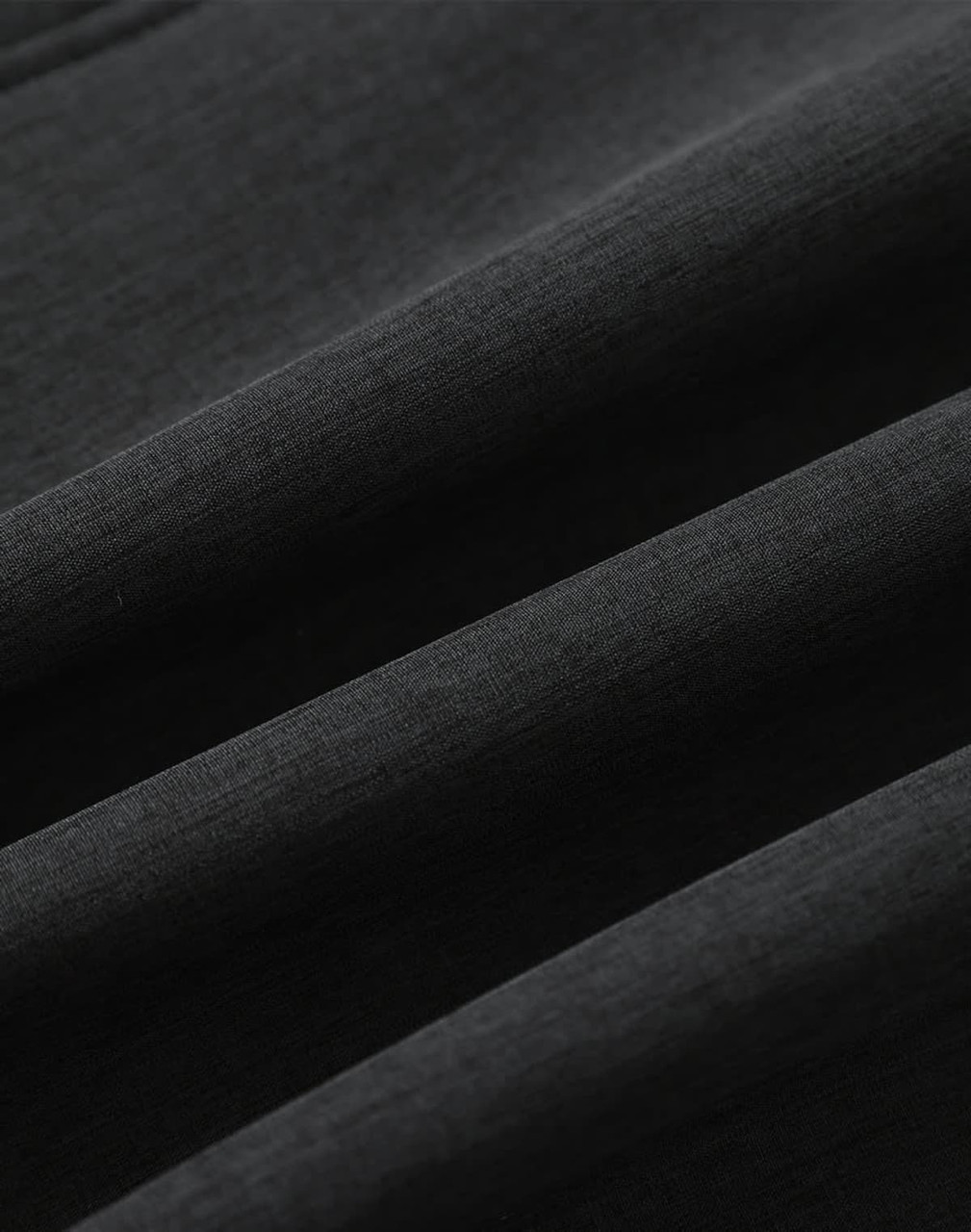 A close-up of a black softshell fabric with a smooth texture, featuring folds and creases.