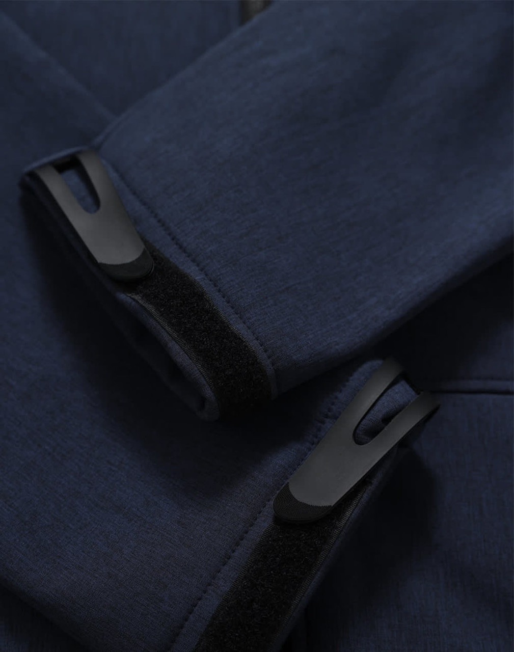 A close-up of a navy softshell hoodie featuring cuff details and a logo.