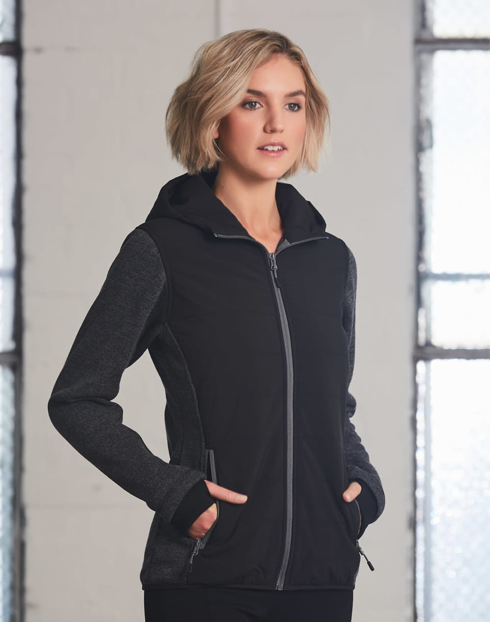 A black and grey ladies' jacket with a hood and zip closure, featuring side pockets and a logo.