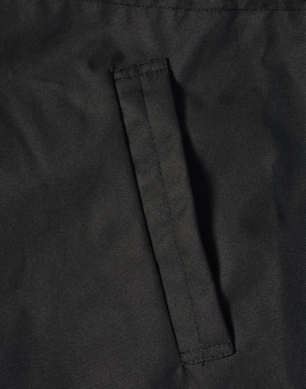 A close-up of a black fabric featuring a stitched pocket on a jacket. The material appears durable and textured.