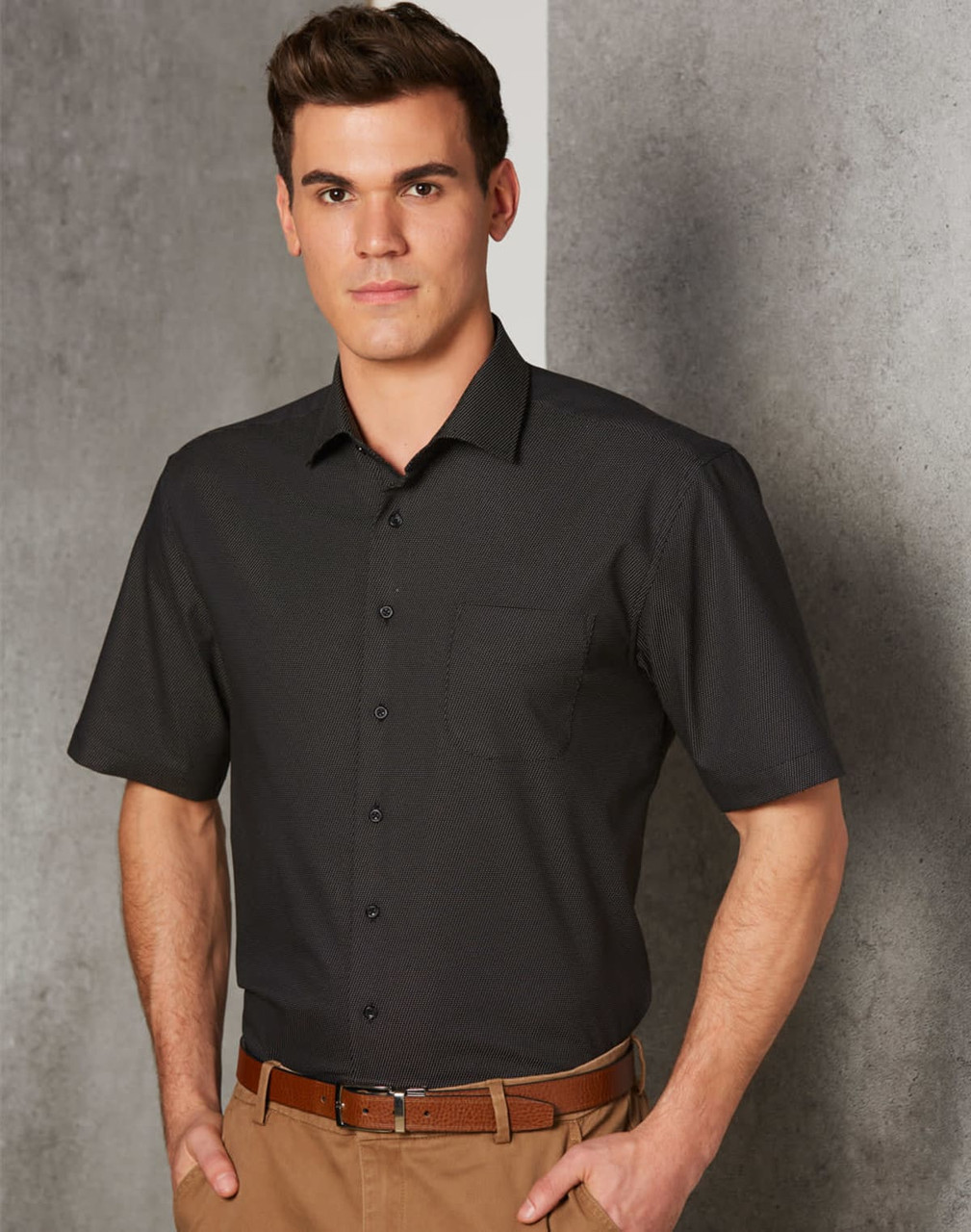 Men's short-sleeve button-up shirt in black with a pin dot pattern and a chest pocket. Features a logo.
