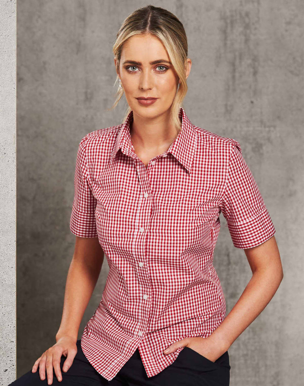 A fitted women's short-sleeve button-up shirt in red and white gingham check pattern, featuring a logo.
