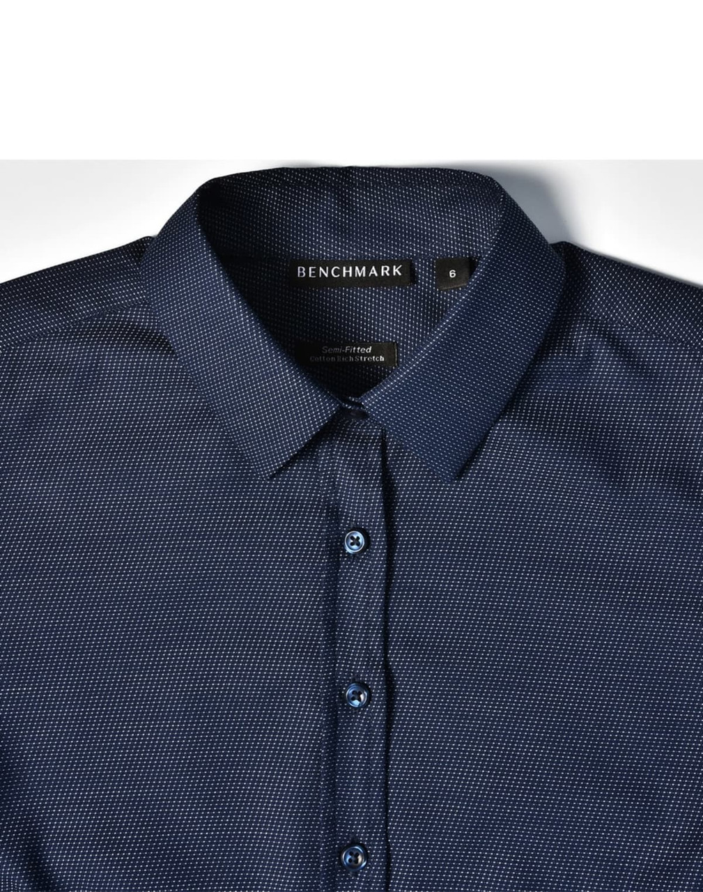 A navy blue pin dot stretch long sleeve shirt with a button-up collar and logo branding on the label.