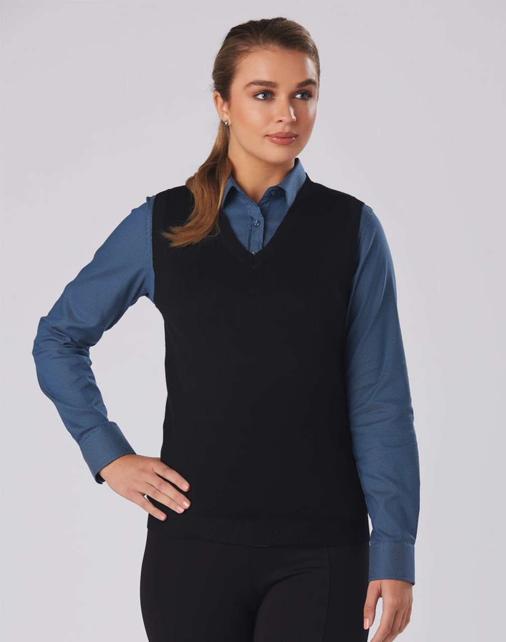 A black women's v-neck vest worn over a blue shirt, featuring a fitted design and casual style.