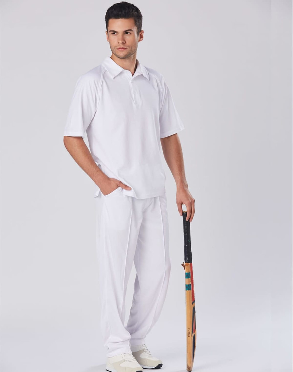 A white men's cricket polo shirt is displayed on a model holding a cricket bat, paired with white trousers.