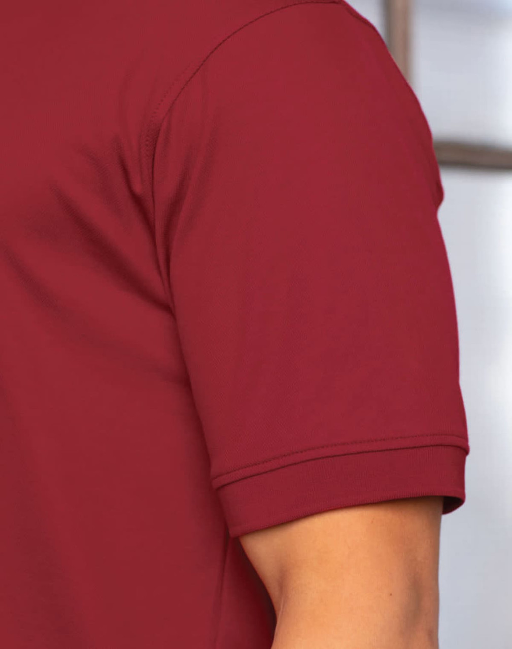 A maroon polo shirt with a short sleeve and a logo on the chest. The fabric appears smooth and lightweight.