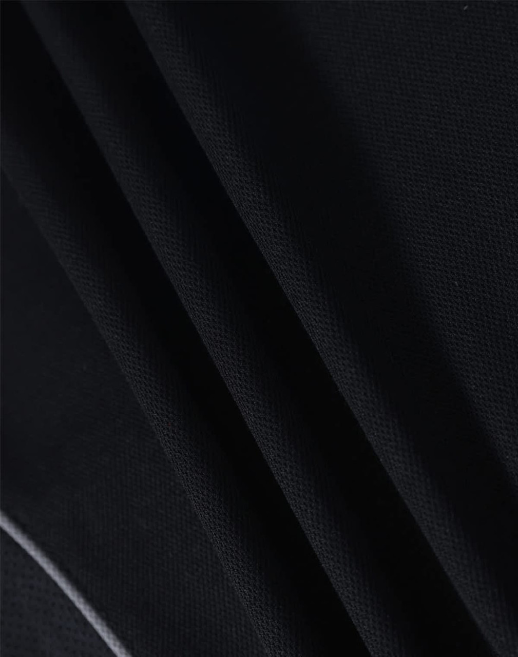 A close-up of textured black fabric, showcasing the material of a polo shirt. It has a logo detail.