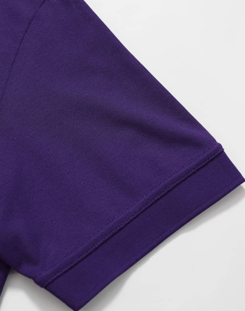 A purple polo shirt sleeve featuring a ribbed cuff and a logo. The fabric appears smooth and breathable.