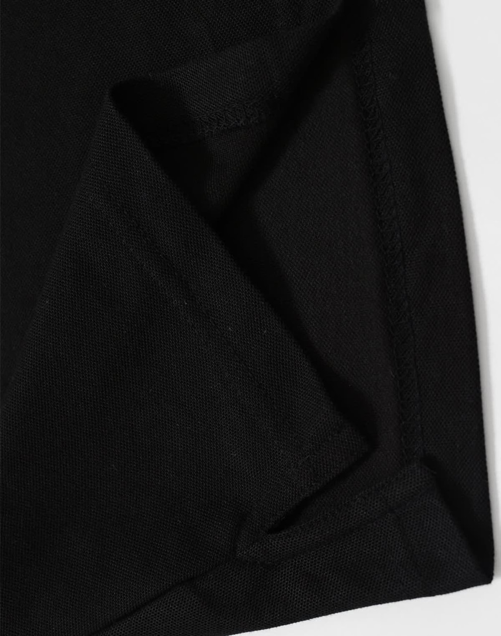 A close-up of black fabric showcasing a folded corner, featuring stitching details and a hidden pocket.