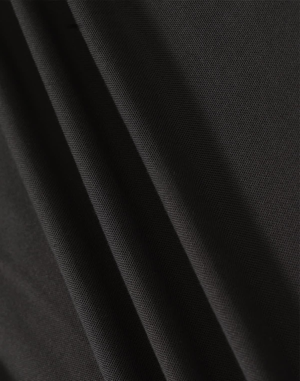 A close-up of black fabric showcasing texture and drape, featuring a subtle weave pattern.