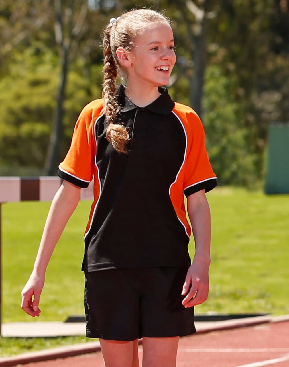 Tri-colour short-sleeve polo shirt in black with orange accents, designed for kids. Features a logo on the chest.