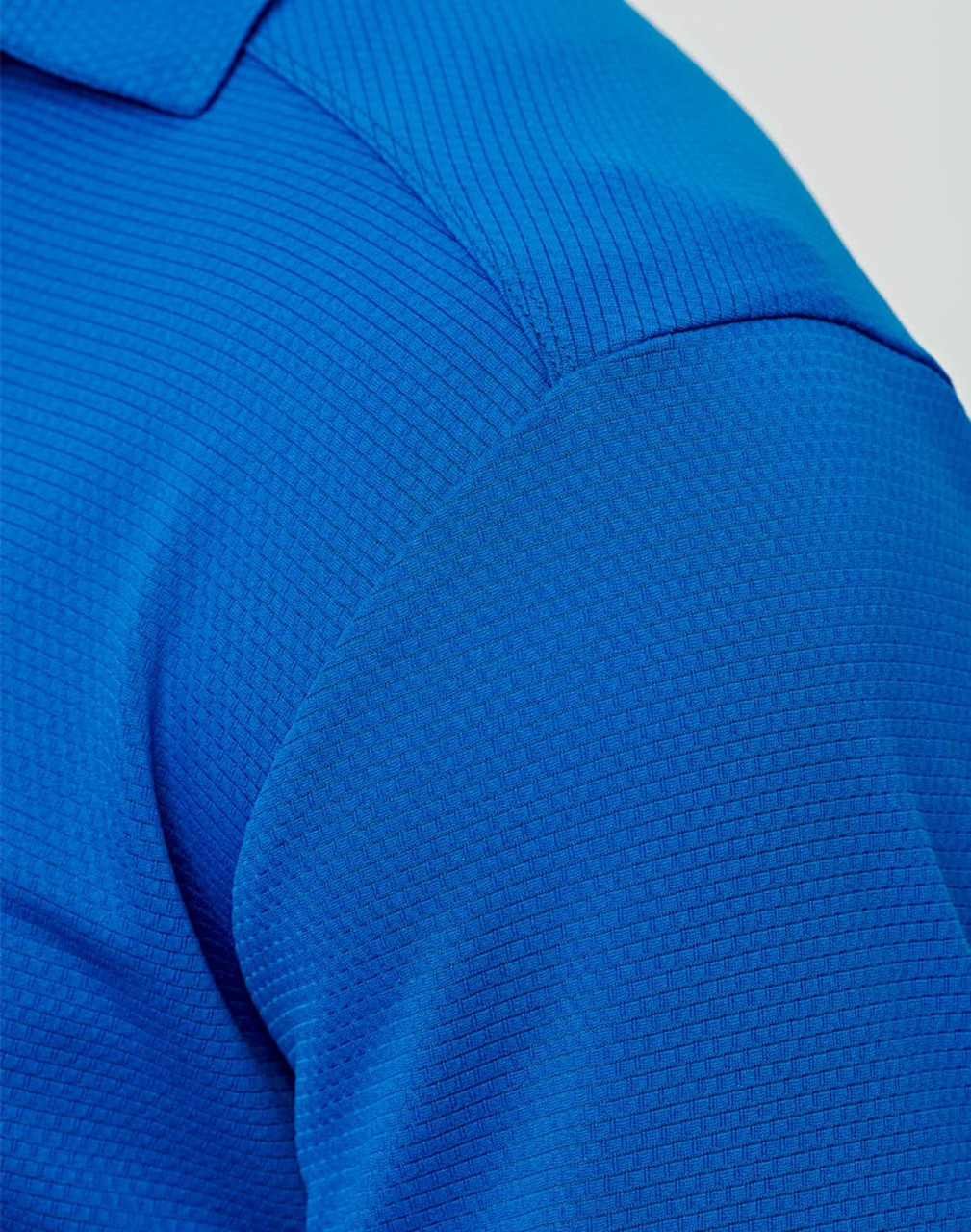 A close-up of a blue men's bamboo charcoal polo shirt, featuring a textured fabric and a collar.