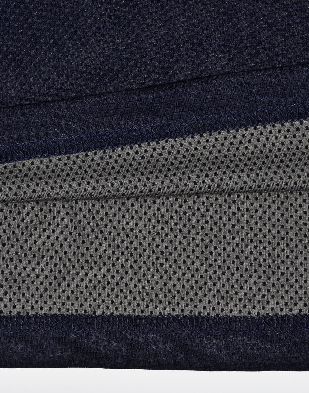 A close-up of a navy and charcoal polo shirt, featuring a textured fabric and a logo.