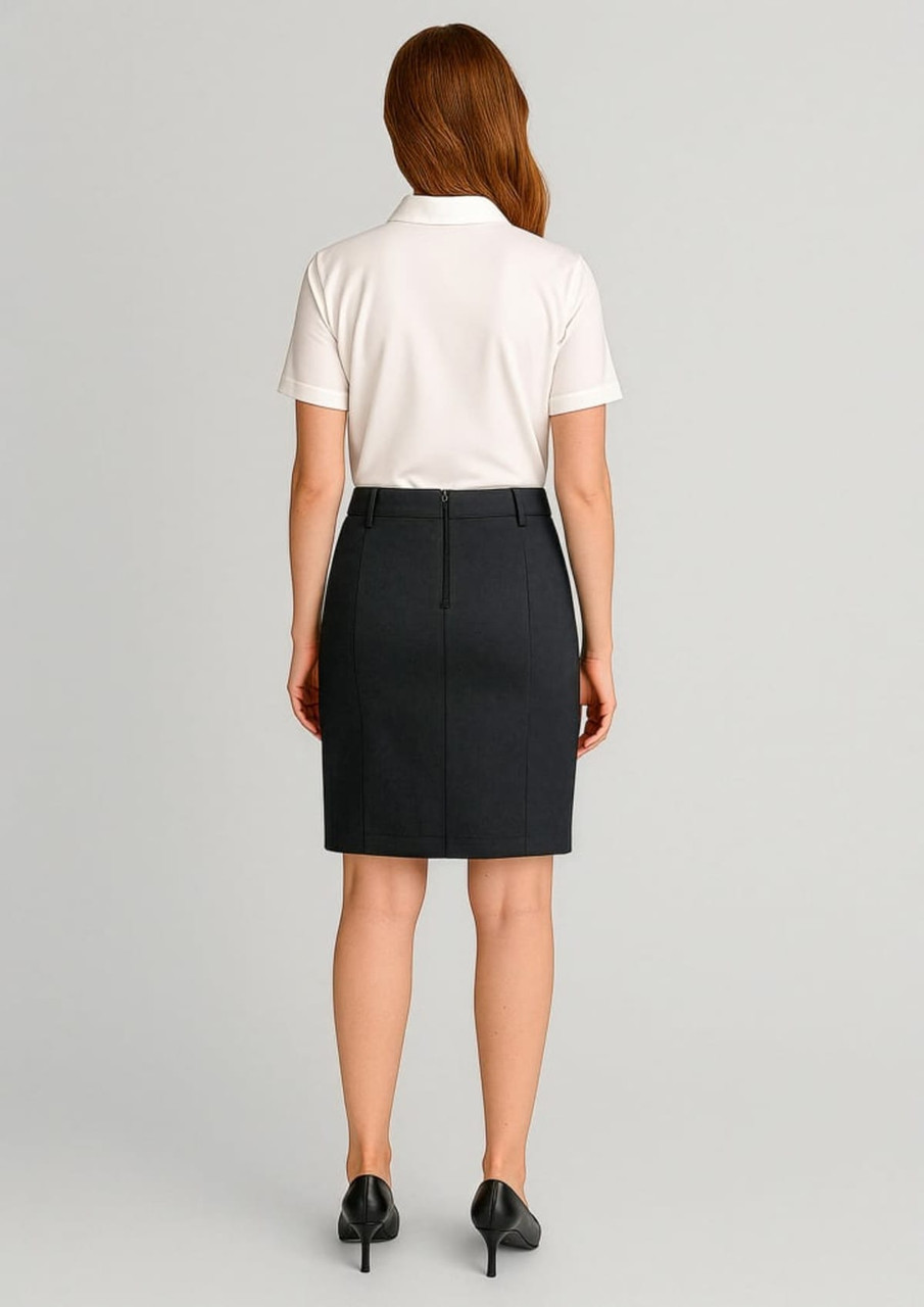 A woman in a white polo shirt and dark mid waist stretch chino skirt, facing away from the camera.