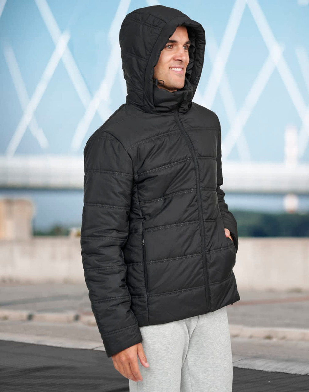 A black unisex sustainable seamless parka jacket with a hood, featuring a quilted design and pockets.