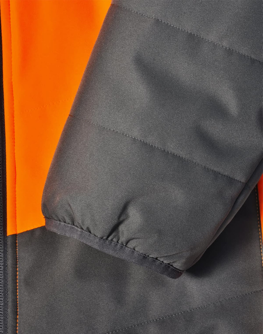 A close-up of a hi-vis quilted safety jacket featuring orange and dark grey colours, with a focus on the sleeve detail.