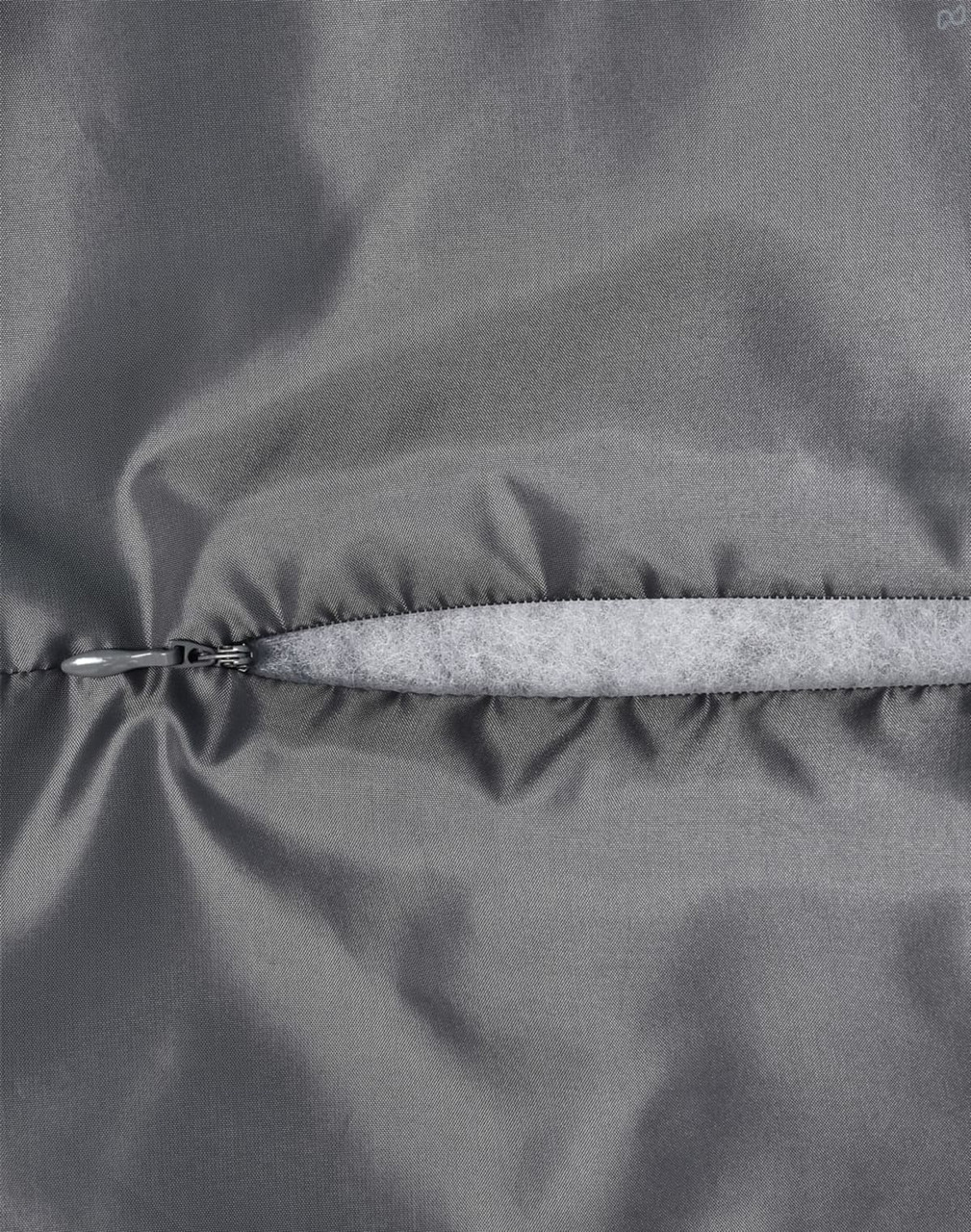 A close-up of a grey quilted fabric with a zip closure, highlighting the texture and stitching details.
