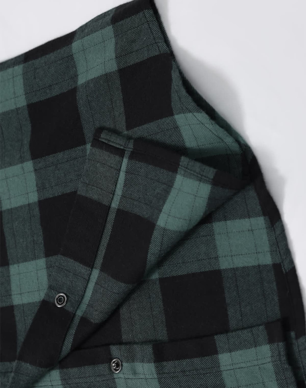A unisex flannel plaid shirt featuring green and black checks, with buttons and a small pocket detail.