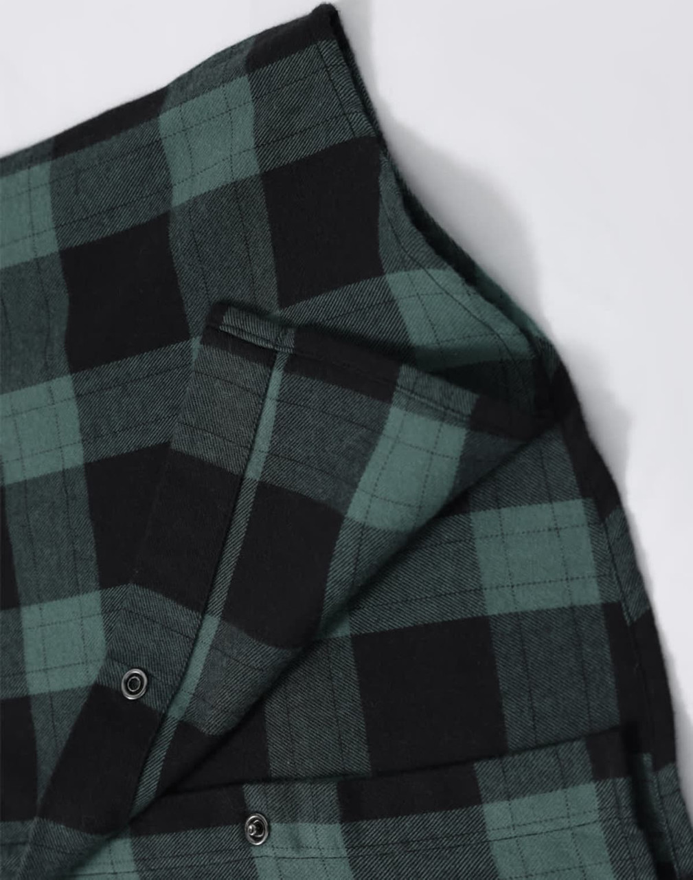 A unisex flannel plaid shirt featuring green and black check patterns, with button-up details and a logo.