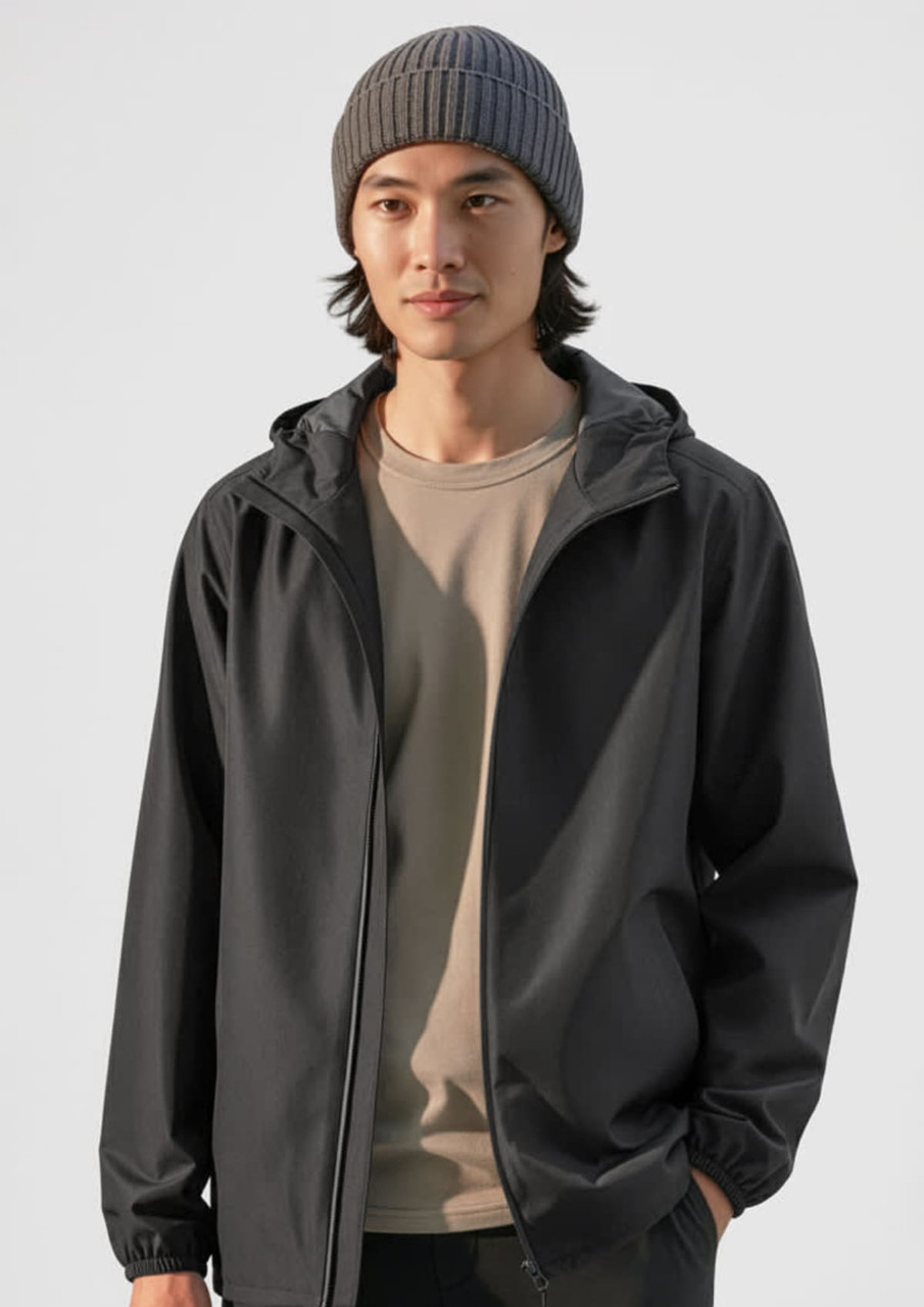 A grey rain jacket is worn by a person with dark hair, complemented by a grey beanie and a beige shirt underneath.