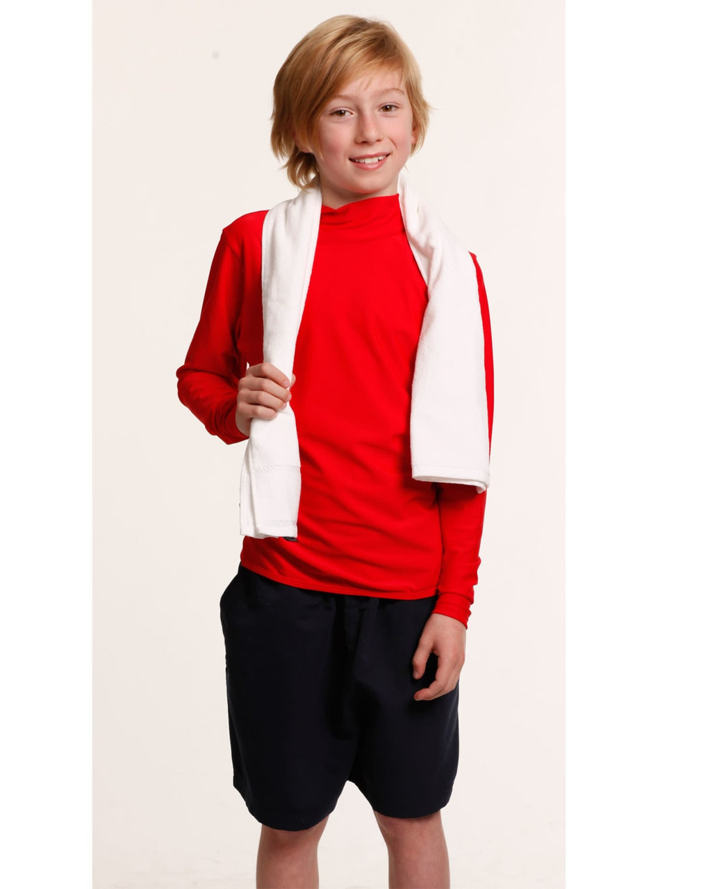 A young boy in a red long-sleeve top and black shorts holds a white terry velour fitness towel.